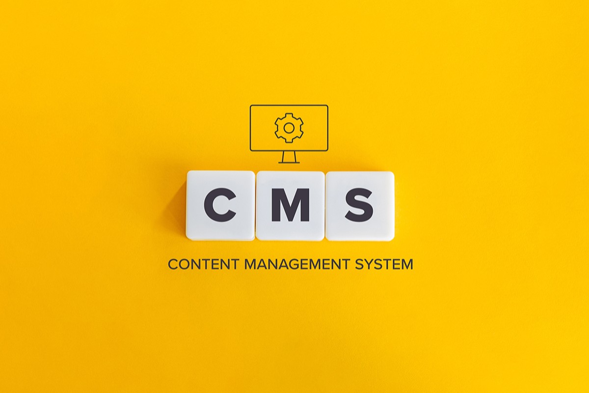 To jest alternatywny opis obrazka. Obrazek ukazuje na żółtym tle trzy białe kostki na każdeej jest po jednej literze C M S (Content Management System). Nad nimi jest ikona przedstawiająca monitor z kołem zębatym w środku.